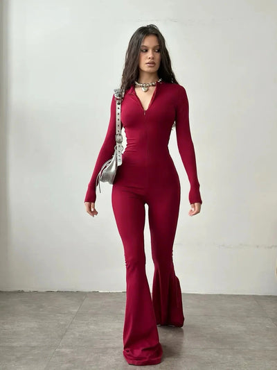 Fashion model wearing a red long-sleeved jumpsuit with flared legs and a stylish handbag.